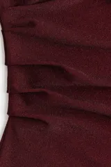 Vestido corto entallado de color bordó, con escote redondo y mangas cortas. Presenta un diseño con pliegues laterales en el hombro y la cintura que crean un efecto drapeado en el frente.