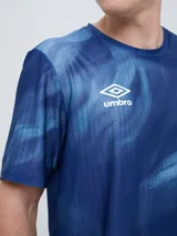 Remera de entrenamiento Umbro del Club Nacional de Football, modelo Press, para hombre. Diseño en tonos de rojo con patrón estampado tipo humo o abstracto, cuello redondo y mangas cortas. Incluye el logo de Umbro y el escudo del club en el pecho.