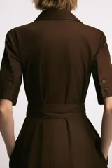 Vestido midi de cuello solapa y escote en pico, con manga corta con vuelta. Presenta bolsillos laterales ocultos, solapas decorativas en el pecho y cierre frontal con botones. Incluye cinturón de lazada en el mismo tejido.