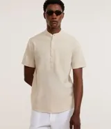 Camisa de manga corta confeccionada en mezcla de lino y algodón, con cuello tipo padre y cierre frontal parcial con botones.