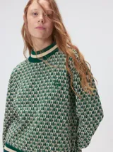Sweater de tejido de punto jacquard con diseño geométrico, cuello redondo y puños acanalados en contraste de color verde y beige.