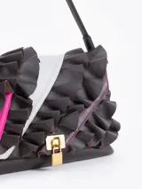 Cartera de hombro negra confeccionada en cuero vacuno, con diseño de solapa frontal decorada con volados de cuero y cierre metálico tipo candado.