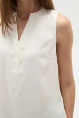 Musculosa de poliéster color blanco, con cuello en V y diseño holgado sin mangas.