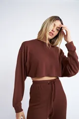 Buzo corto de tela rib, color marrón, con mangas largas y cuello redondo.