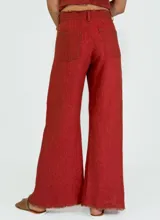 Pantalon de corte recto y pierna ancha, confeccionado en lino color beige. Presenta un diseño de tiro medio con aberturas laterales en el ruedo y detalle de bordes desflecados.