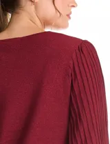 Buzo de tejido lurex marca Nanette, con cuello redondo y mangas largas con diseño plisado. Presenta puños ajustados con aplique de botones decorativos.