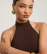 Blusa marrón oscuro con cuello halter y corte peplum, ajustada al cuerpo con pences frontales.