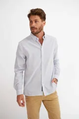 Camisa de manga larga con diseño de rayas verticales blancas y azules, cuello camisero y cierre frontal con botones.