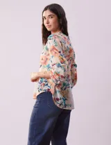 Blusa de gasa estampada con cuello a la base plisado y escote en V. Tiene apertura central con botones de nácar y mangas largas fruncidas. Incluye musculosa interna.
