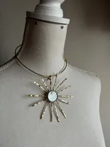 Gargantilla dorada con dije en forma de sol con centro de nácar.