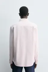 Camisa de corte regular fit confeccionada en tejido de algodón con diseño de rayas finas. Presenta cuello solapa, cierre frontal de botones y manga larga con puños abotonados.