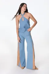Pantalón de jean azul oscuro de pierna ancha y tiro medio, con paneles laterales en contraste de color marrón. Presenta costuras pespunteadas en tono tostado y terminación desmechada en el bajo.