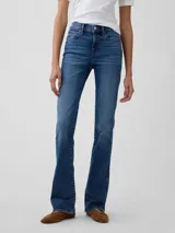 Jean de corte baby boot con tiro medio y lavado azul medio, confeccionado en denim con costuras reforzadas y cierre frontal con botón y cremallera.