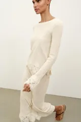 Falda midi de tejido rústico en color beige, con tiro medio, cintura elástica y detalle de aplicación de crochet en el bajo.