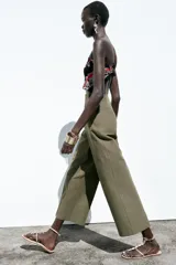 Pantalón de lino negro, de tiro alto, con bolsillos delanteros de vivo, pernera recta y cierre frontal con cremallera, botón interior y gancho metálico.