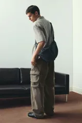 Pantalón cargo de sarga de algodón suave con efecto lavado, color marrón verdoso. Presenta cintura elástica con cordón ajustable, bolsillos laterales, bolsillos cargo con solapa en las piernas y cordón ajustable en el bajo. Corte holgado.