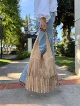 Cartera tipo hobo de cuero color beige con flecos en dos niveles.