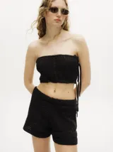 Top strapless tipo crochet color negro, de diseño tejido con detalles en ochos y puntos calados, con espalda descubierta y tiras ajustables en el lateral.