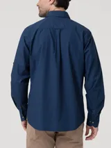 Camisa de hombre color azul marino, de manga larga con presillas para enrollar, cuello clásico, cierre de botones de madera y bolsillo en el pecho con logo bordado. Confeccionada en popelina 100% algodón orgánico.