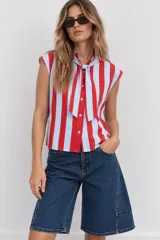 Blusa sin mangas a rayas verticales rojas y celestes, con cuello camisero y tiras frontales para anudar.