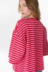 Remera oversize de manga corta a rayas horizontales en tonos rojo y rosado, con cuello redondo.
