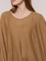 Poncho de calce holgado color marrón, confeccionado en tejido fino de punto suave, con cuello redondo y diseño de caídas laterales amplias de ruedo asimétrico.