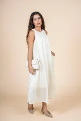 Vestido midi color crema, de corte recto y cuello redondo. Presenta bolsillos laterales y diseño sin mangas.