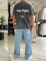 Remera oversize de efecto gastado color celeste, con cuello redondo y mangas cortas. Estampado frontal pequeño con el texto "Top Style" y gran estampado en la espalda con el mismo texto, la frase "Dream big. Work hard. Make it real.", el año "SINCE 2021" y un código de barras.