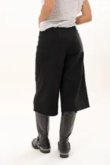 Bermuda de corte amplio y tiro alto en color negro, con cierre frontal de botón y bolsillos laterales.