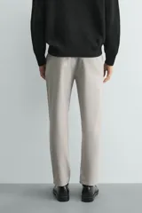 Pantalón chino de corte slim fit, confeccionado en tejido elástico. Presenta bolsillos frontales, bolsillos traseros de vivo con botón y cierre frontal con cremallera y botón.