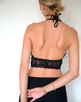 Top tipo bralette de encaje negro con diseño halter y escote profundo, confeccionado en tejido de encaje con patrón floral.