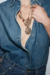 Pack de dos collares de diferente longitud con eslabones metálicos plateados. El primer collar presenta un colgante de corazón labrado con incrustaciones de piedra y cristal. El segundo collar incluye un colgante de medalla labrada con detalles en resina a color.