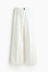 Pantalón jean de denim de algodón rígido, color blanco, de corte wide leg con tiro alto, bolsillos delanteros con ribete trenzado y pliegues marcados.