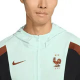 Campera deportiva Nike de la selección de Francia, con cierre frontal completo y capucha. Presenta un diseño en color verde agua con paneles laterales en negro y marrón, logo de la marca y escudo de la federación en el pecho.