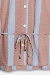 Camisa sin mangas de cuello camisero con estampado de rayas verticales en tonos marrón y celeste, cierre frontal con botones y cordones ajustables en los hombros y la cintura.