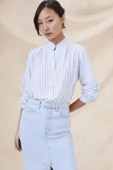 Camisa de manga larga con cuello mao y estampado a rayas verticales celestes y blancas.
