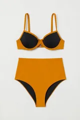 Conjunto de bikini combinado en negro y mostaza, compuesto por un corpiño con aros y breteles finos, y una bombacha de tiro medio con detalles en contraste.