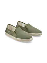 Alpargatas tipo slip-on color verde oliva, confeccionadas con materiales reciclados. Presentan un diseño con detalle bordado de espina de pescado en el lateral, refuerzo de gamuza en el talón y suela con borde de yute trenzado.