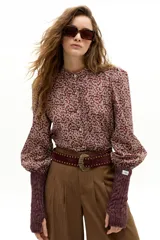 Camisa de algodón con estampado floral, cuello mao y cierre frontal con botones de nácar. Presenta mangas largas abullonadas con puños elásticos y detalle de volado en la cartera de botones.