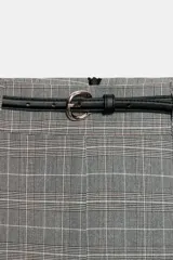 Falda midi de corte recto y tiro alto, con estampado de cuadros en tonos grises. Presenta una abertura frontal en el bajo y viene acompañada de un cinturón fino a contraste.
