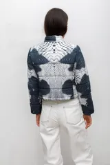 Campera puffer corta con cuello alto, cierre frontal con botones a presión y estampado abstracto de puntos en tonos azul oscuro y blanco.