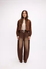 Chaqueta de efecto gamuza en color marrón, con diseño de inspiración western que presenta flecos en la parte frontal y en la espalda. Cuenta con cuello clásico, cierre frontal con botones metálicos a presión y mangas largas.