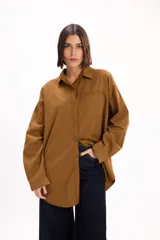 Camisa de corte oversize color marrón, con cuello clásico, cierre frontal de botones y bolsillo en el pecho.