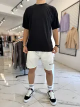 Bermuda de jogging color beige, con bolsillos laterales y estampa con texto blanco en la pierna izquierda.