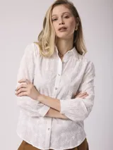 Camisa blanca de algodón con bordado floral, corte clásico, cuello camisero y mangas largas con puños abotonados.