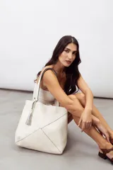 Bolso tipo shopper color rojo, confeccionado en 100% cuero vacuno, con diseño geométrico de paneles y detalle de fleco decorativo colgante.