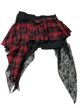 Minifalda asimétrica de cuadros tartán en rojo y negro, con detalles de encaje negro, una cadena metálica colgante y hebilla decorativa.