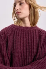Sweater bordó de punto grueso con cuello redondo y mangas ranglan.