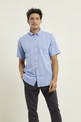 Camisa de hombre color azul melange, de manga corta, con cuello abotonado y un bolsillo en el pecho. Cierre frontal con botones marrones.