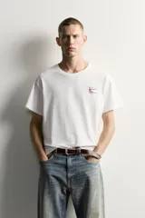 Camiseta relaxed fit de color blanco con efecto lavado, cuello redondo y manga corta. Presenta un pequeño estampado a contraste en el pecho izquierdo.